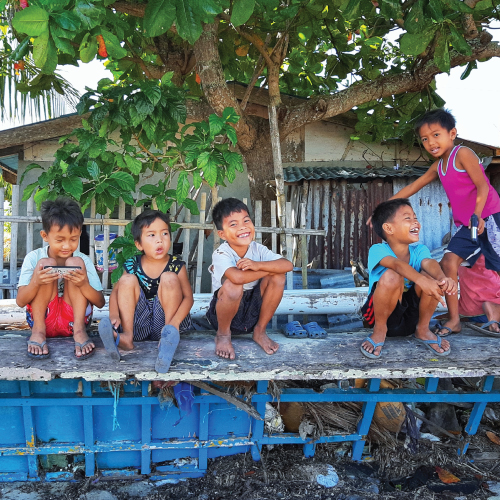 A group of children sitting on a bench

Description automatically generated