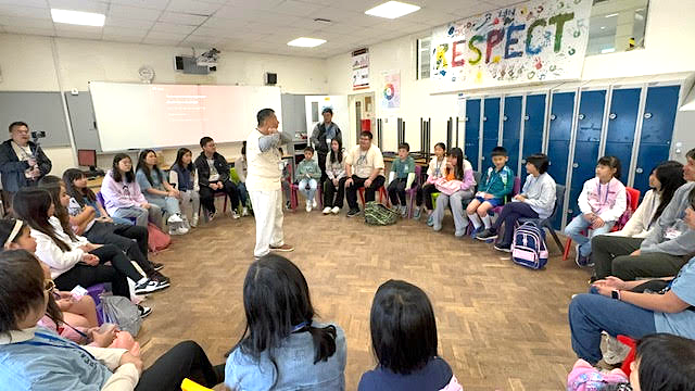 A person standing in a circle with a group of people sitting in chairs

Description automatically generated