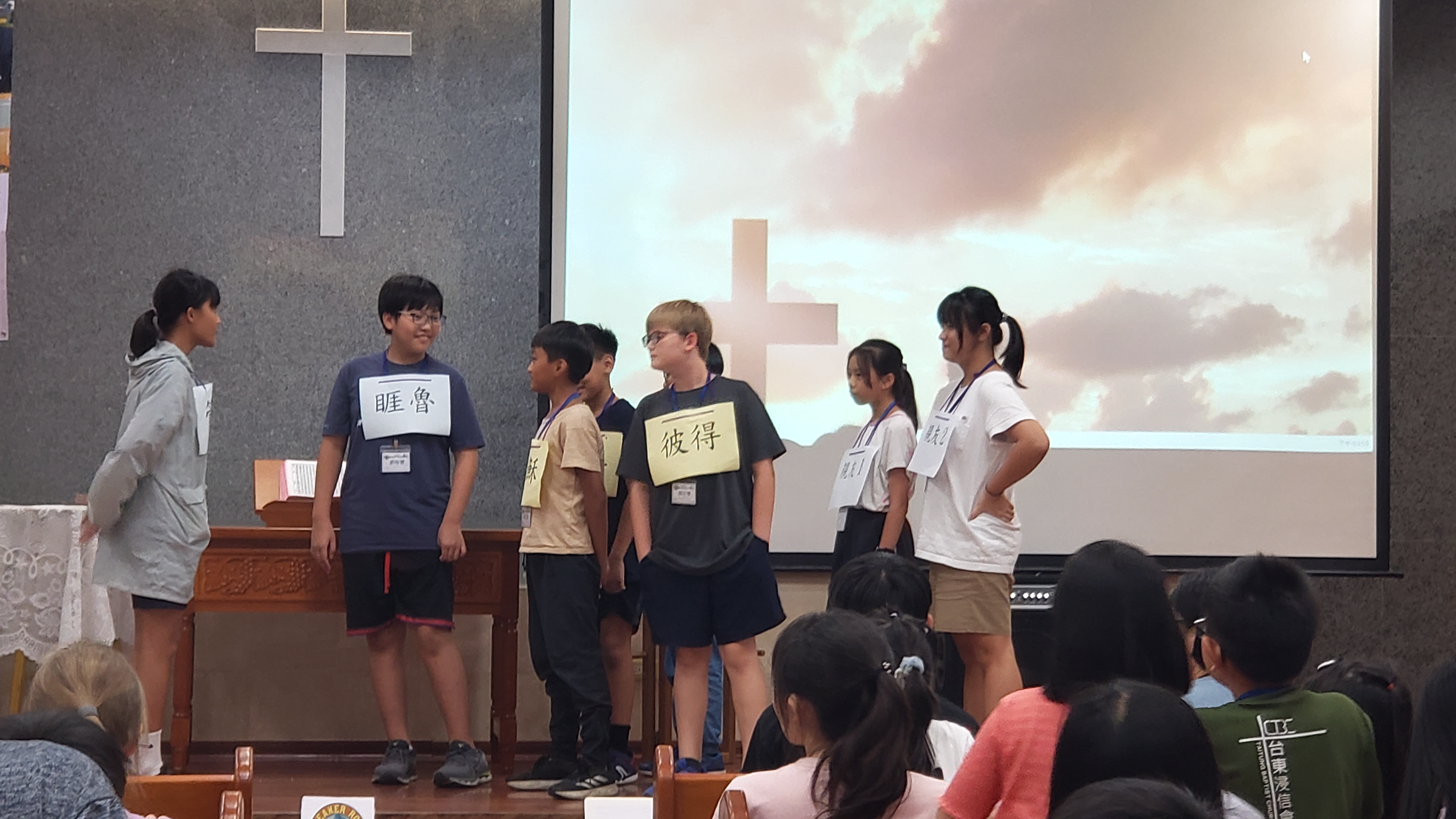 A group of people standing in front of a projection screen

Description automatically generated