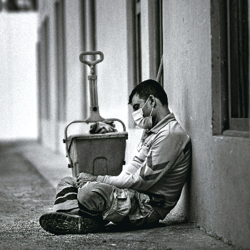 A person wearing a face mask sitting on the ground

Description automatically generated